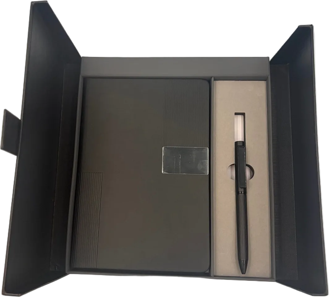 Kit en caja negra abierta con libreta negra de placa metálica y pluma negra en su compartimento