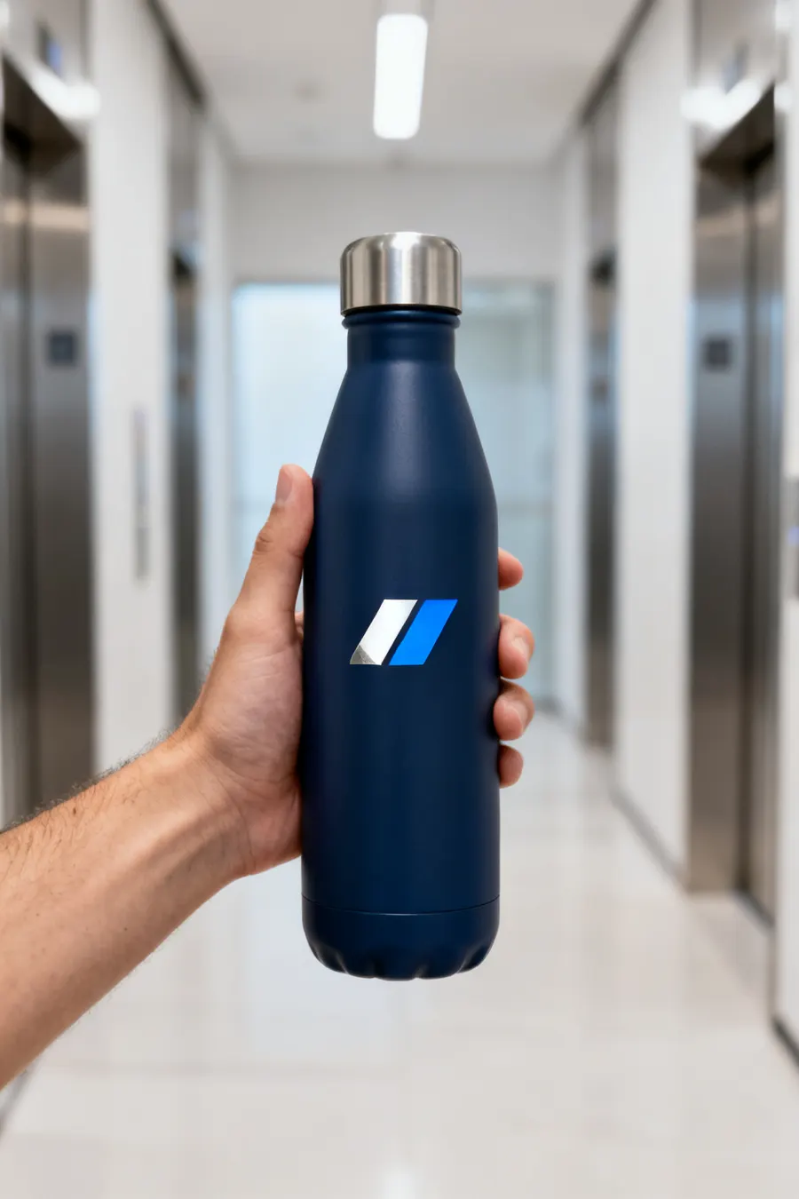 Mano sosteniendo una botella térmica azul marino con logo