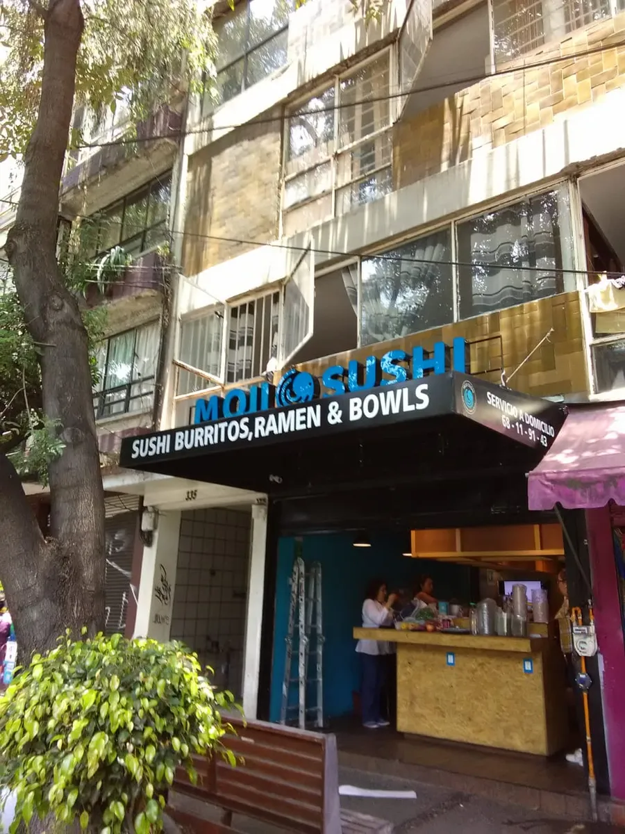 Fachada del restaurante Moji Sushi con el toldo impreso y el letrero de letras azules